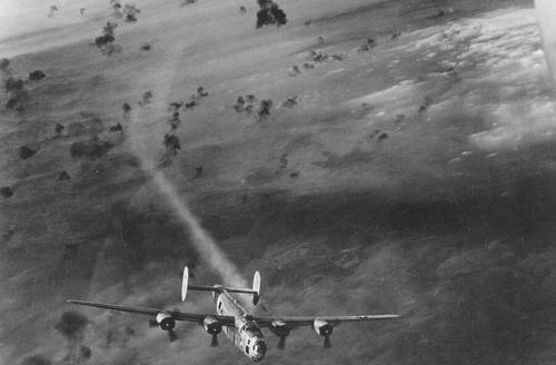 Бомбардировщик B-24 выныривает из облака разрывов снарядов зенитных орудий с дымящимся двигателем
